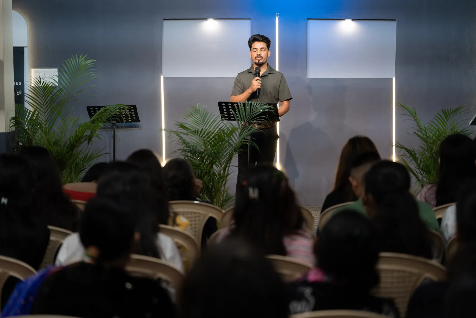 A speaker stands at the front of the church hall while the congregation sits and listens.